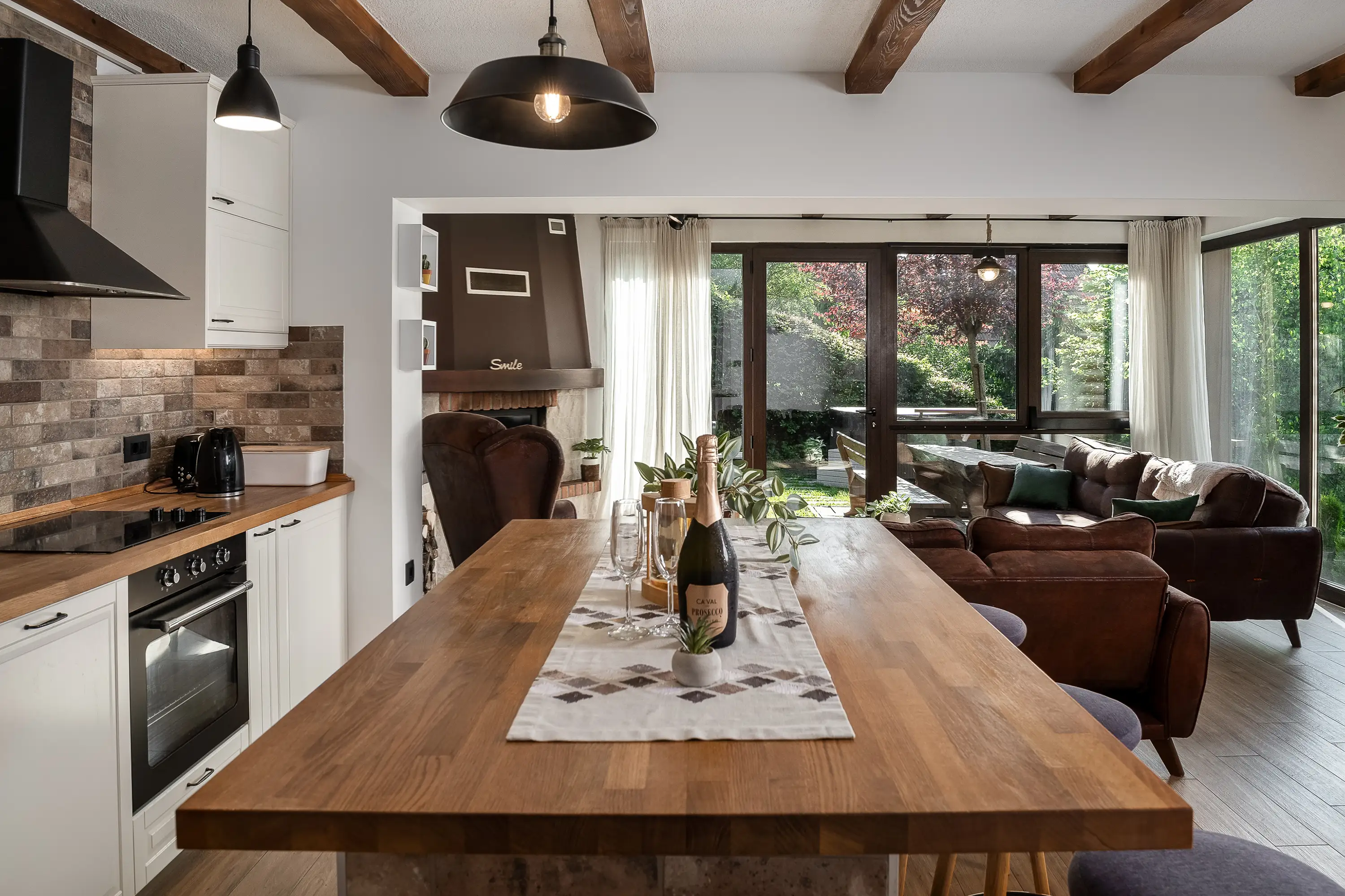 Pregled otvorene kuhinje i dnevnog boravka s drvenim otokom i gredama