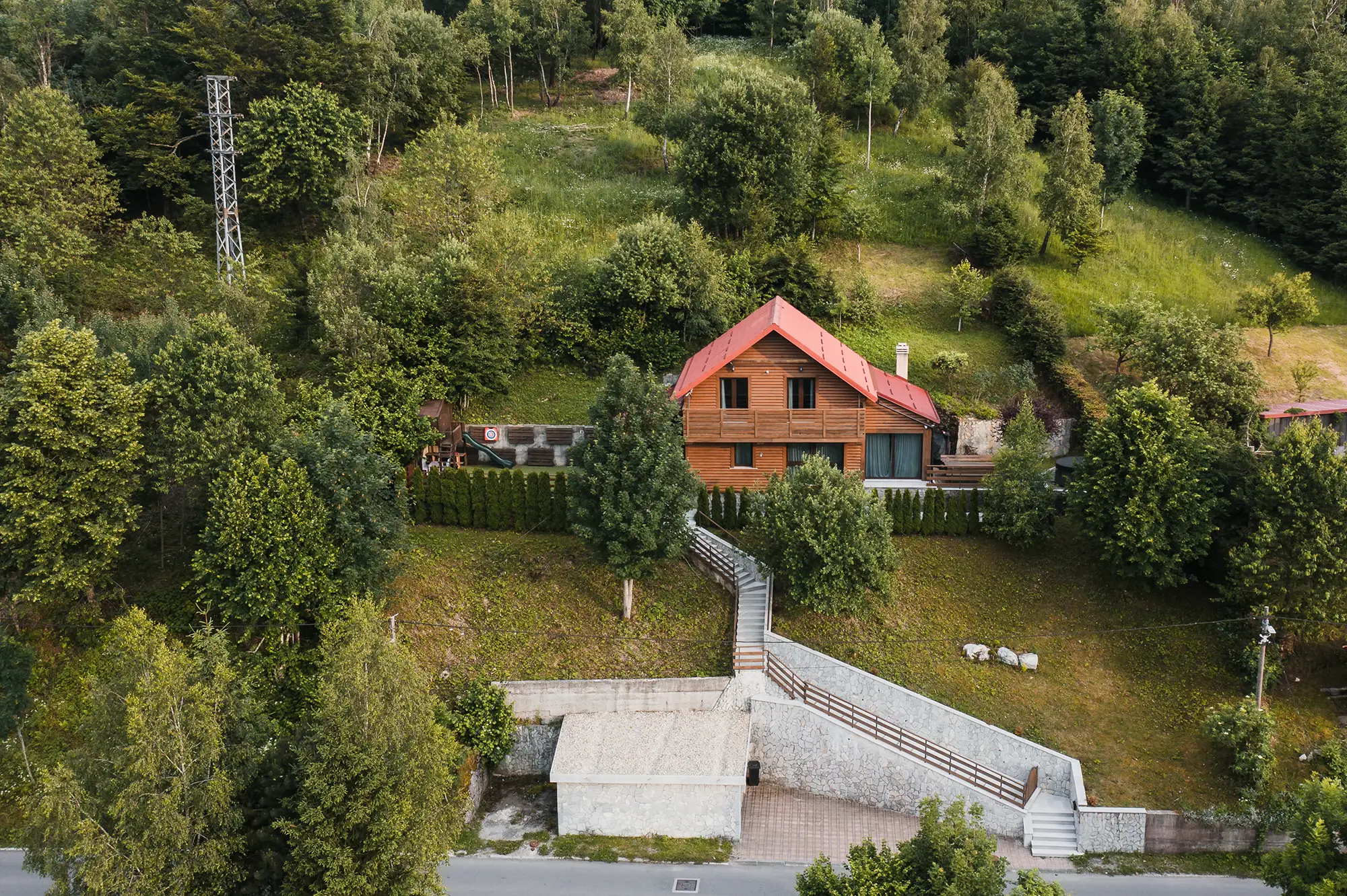 Pogled iz zraka na Villu Fužine s crvenim krovom, kamenim stubištem i okolnom šumom